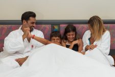 Famiglia che sorride nel letto in camera hotel